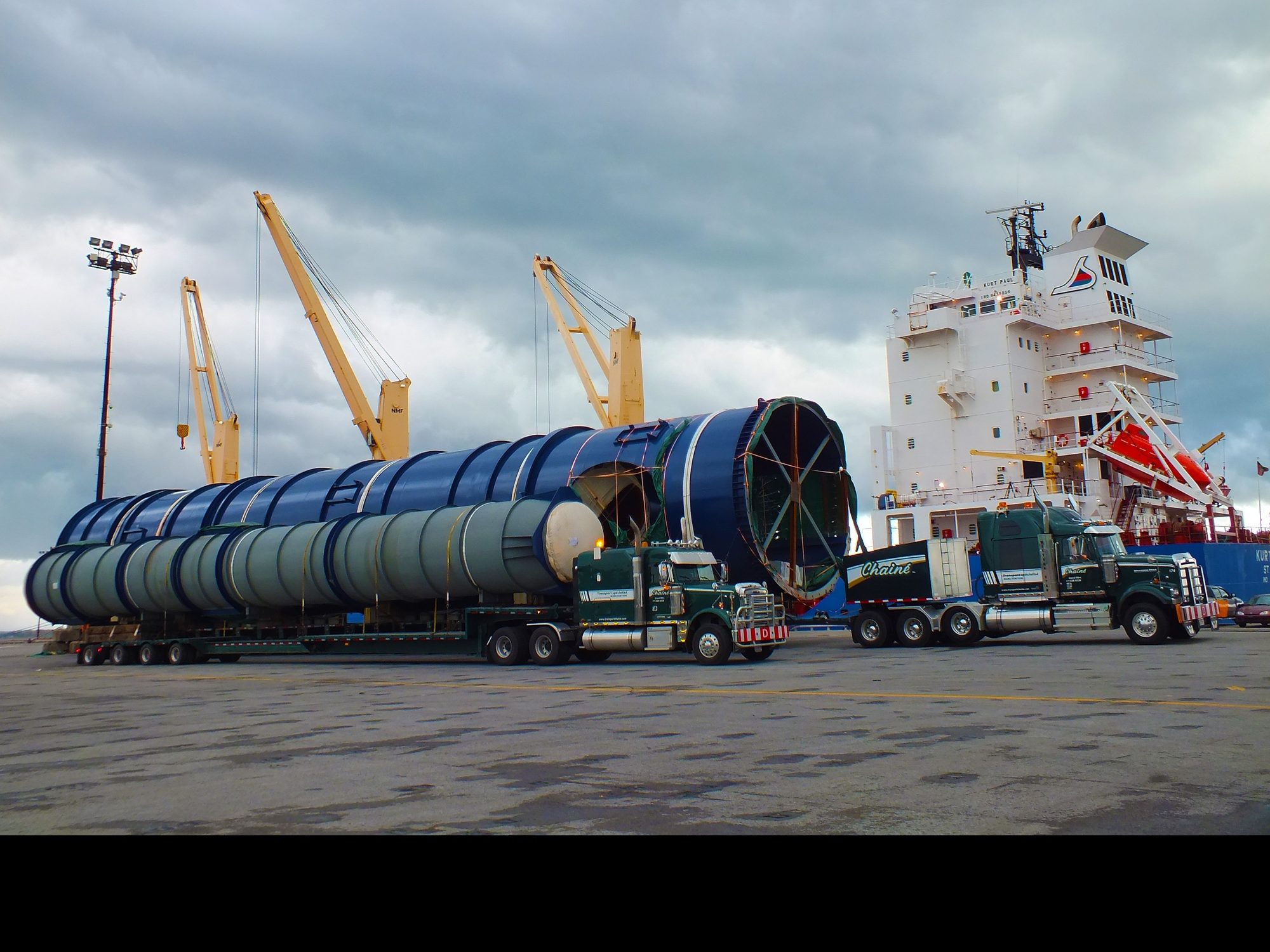 Les segments de la tour de refroidissement sur modules Goldhofer au quai du Port de Bécancour, le navire et ses grues derrière
